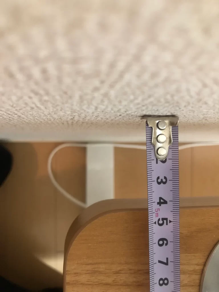 デスクの脚先が壁に当たり、天板と壁の間に約5cmの隙間ができている様子を真上から撮影