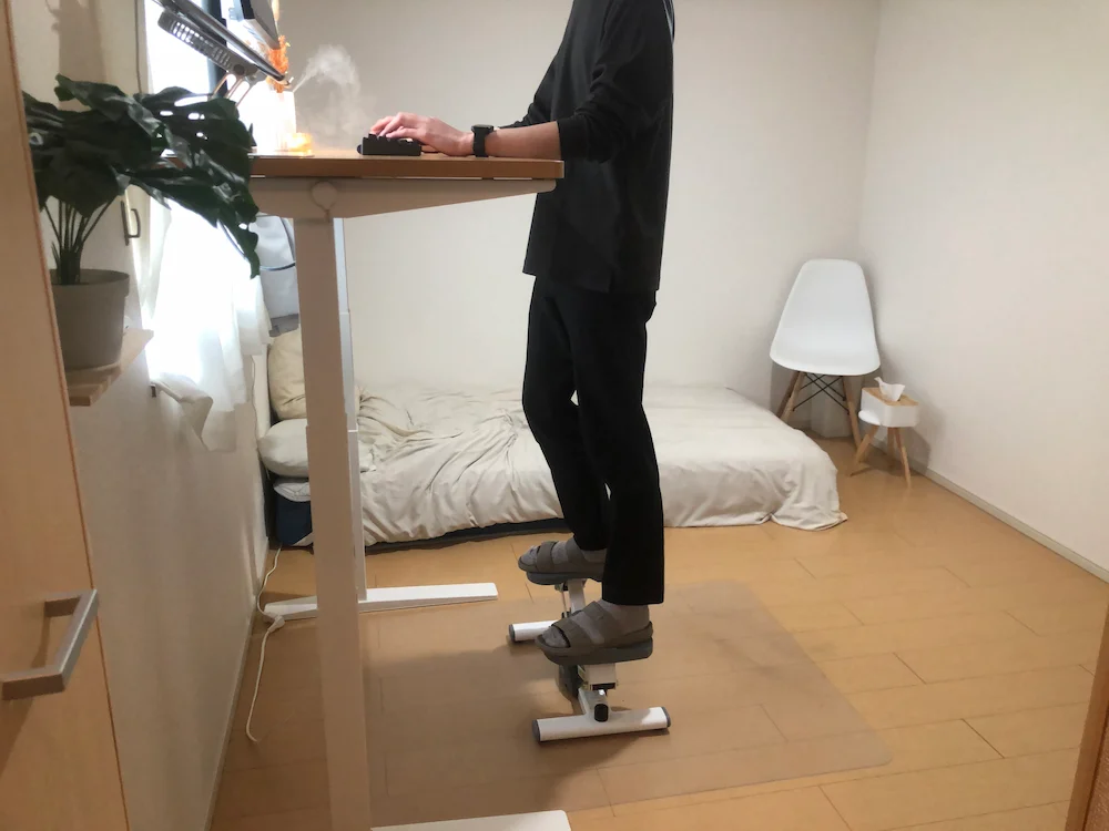 電動昇降デスクの下にステッパーを設置し、動画を見ながら運動する足元