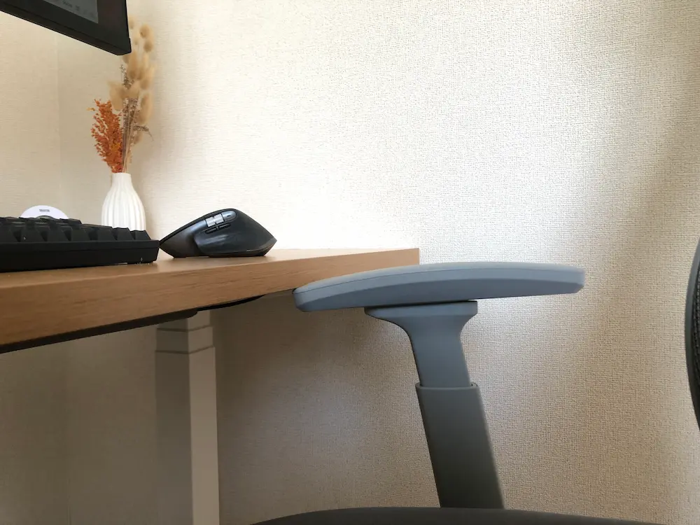 昇降デスクが降下する際、椅子の肘置きに当たりそうになっている注意喚起写真。