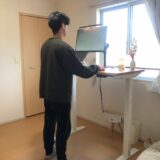 FlexiSpot E7を使って立ち作業する在宅ワーカーのデスク風景。